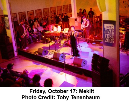 A band performs on stage in front of an audience at BRIC Jazz Fest 2025. The lead singer stands at the microphone, with musicians playing various instruments behind her. The room is warmly lit and filled with seated spectators.